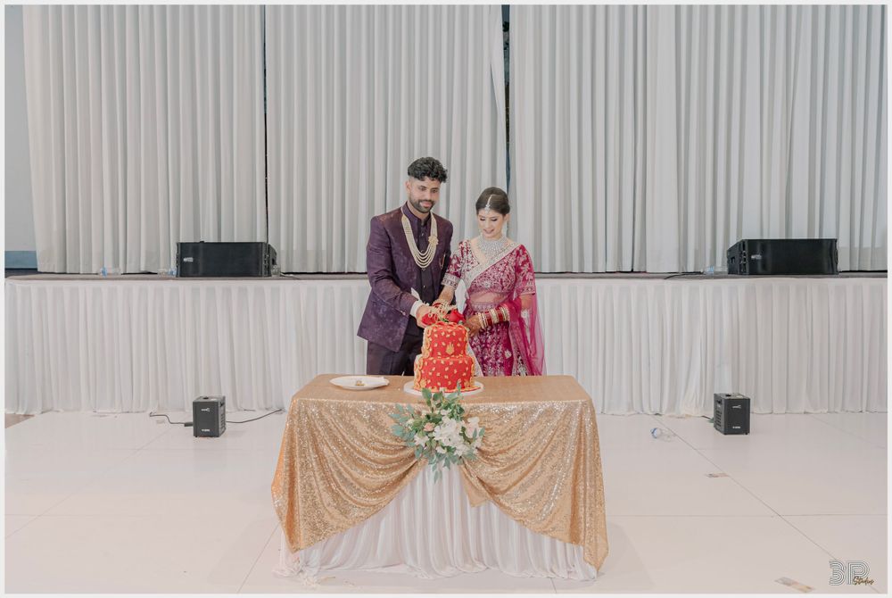 A couple poses at their wedding reception with decorative backdrop and golden tablecloth.