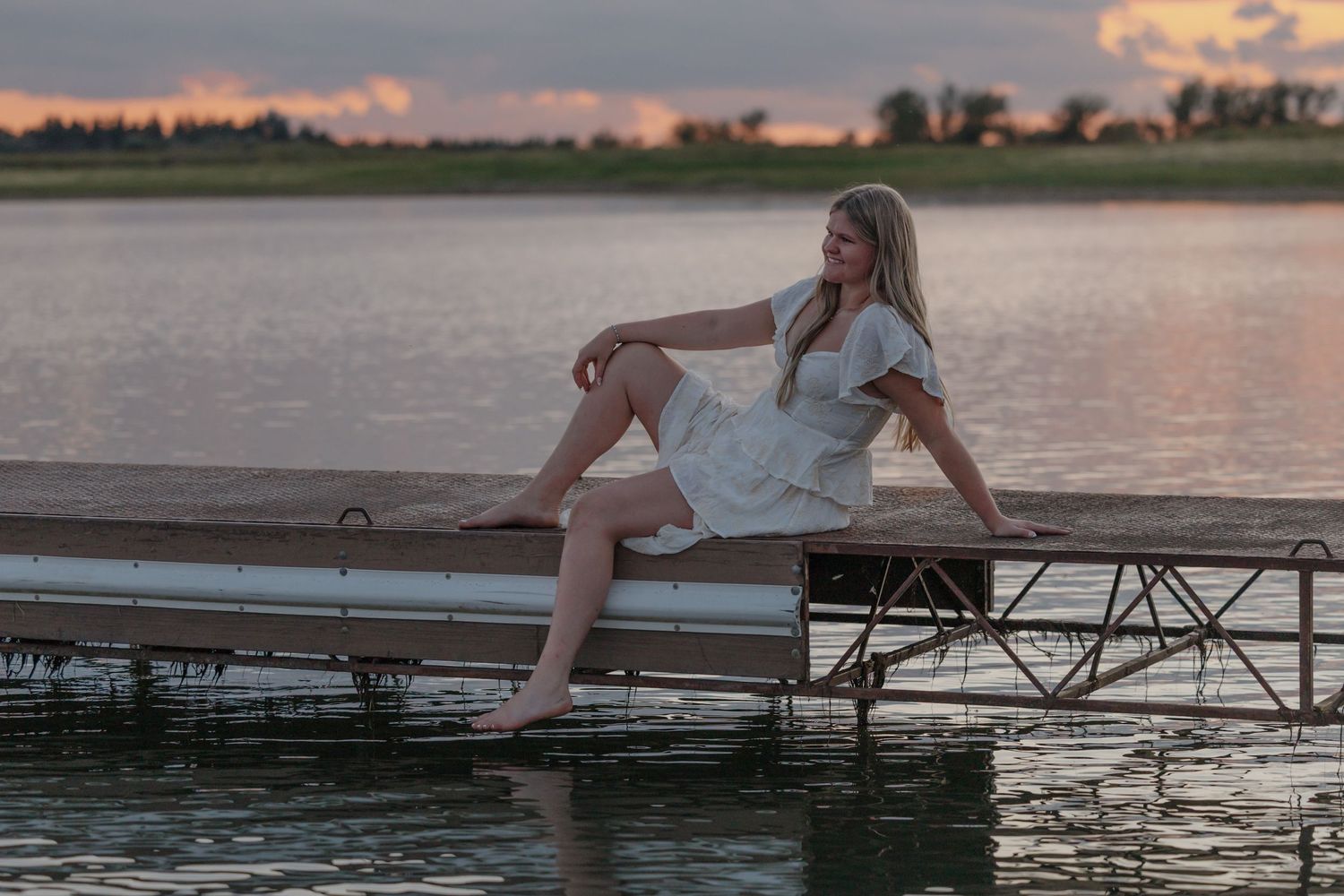 Senior portrait of a high school student on a dock during sunset in Garrison ND with golden hour lighting