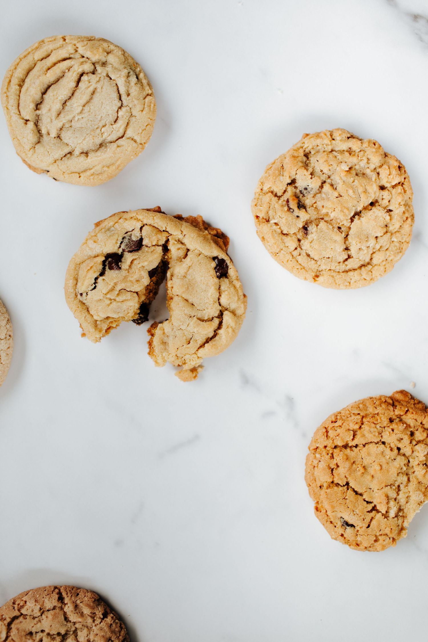 Homemade peanut butter cookies with crackled tops on white marble surface.