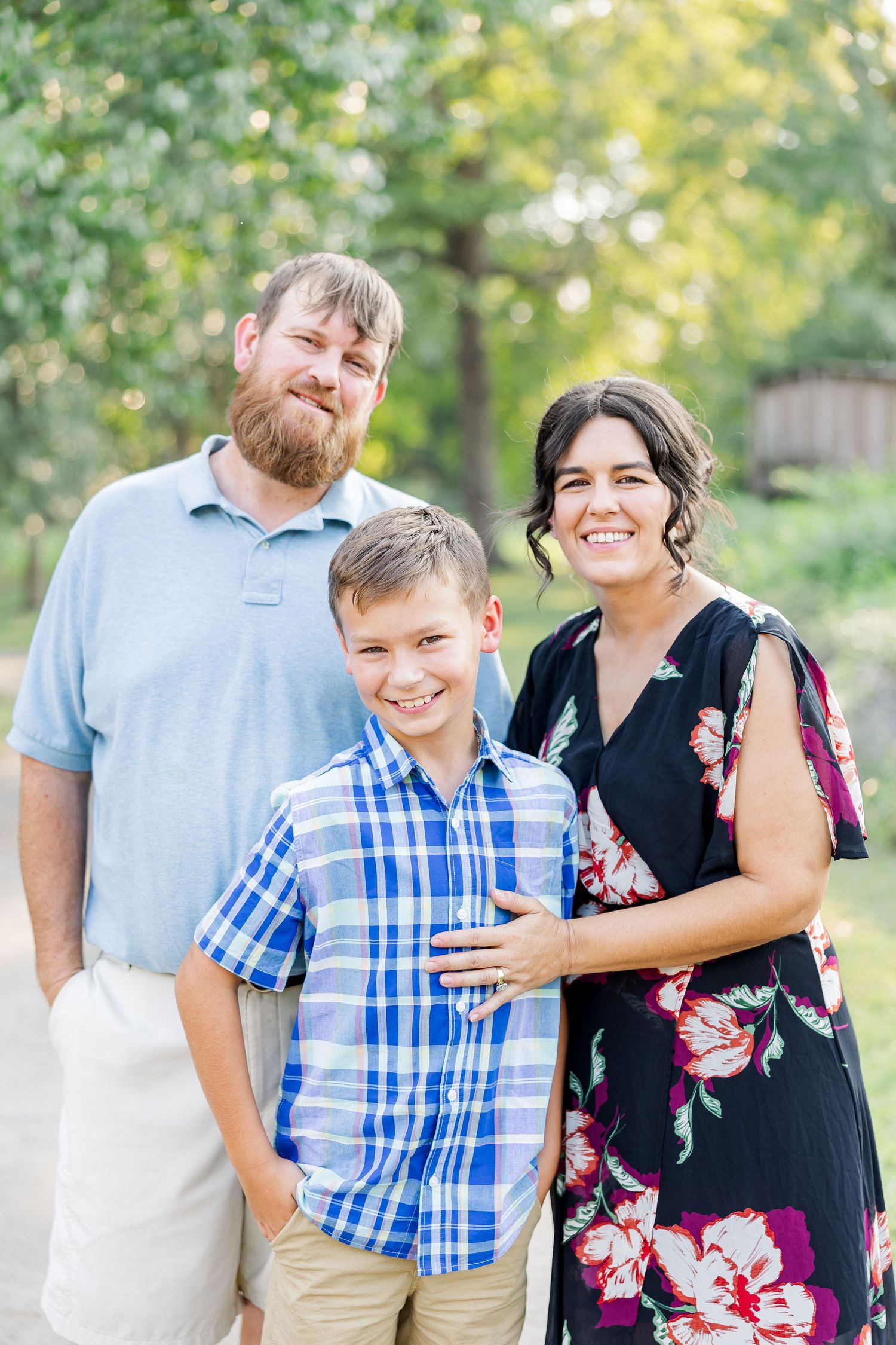 Family portrait session outdoors with natural lighting and greenery backdrop.