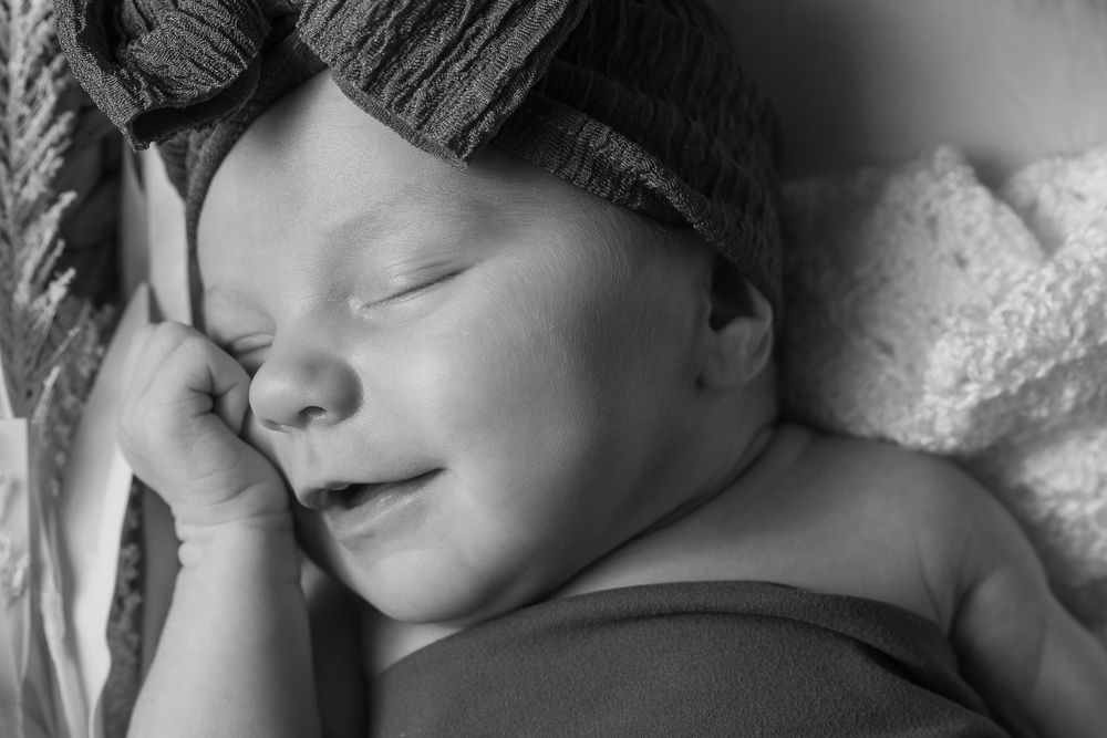 Black and white portrait of peaceful sleeping baby with hand near face.