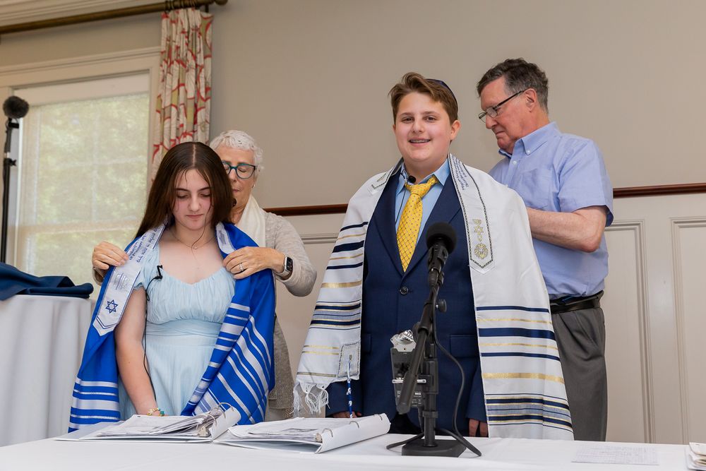 Two people in formal attire stand at a table during a religious ceremony.