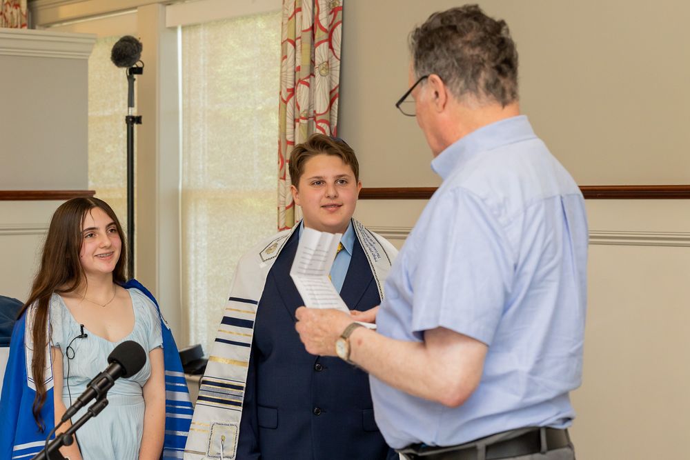 Three people stand at a podium during a formal ceremony with microphones.