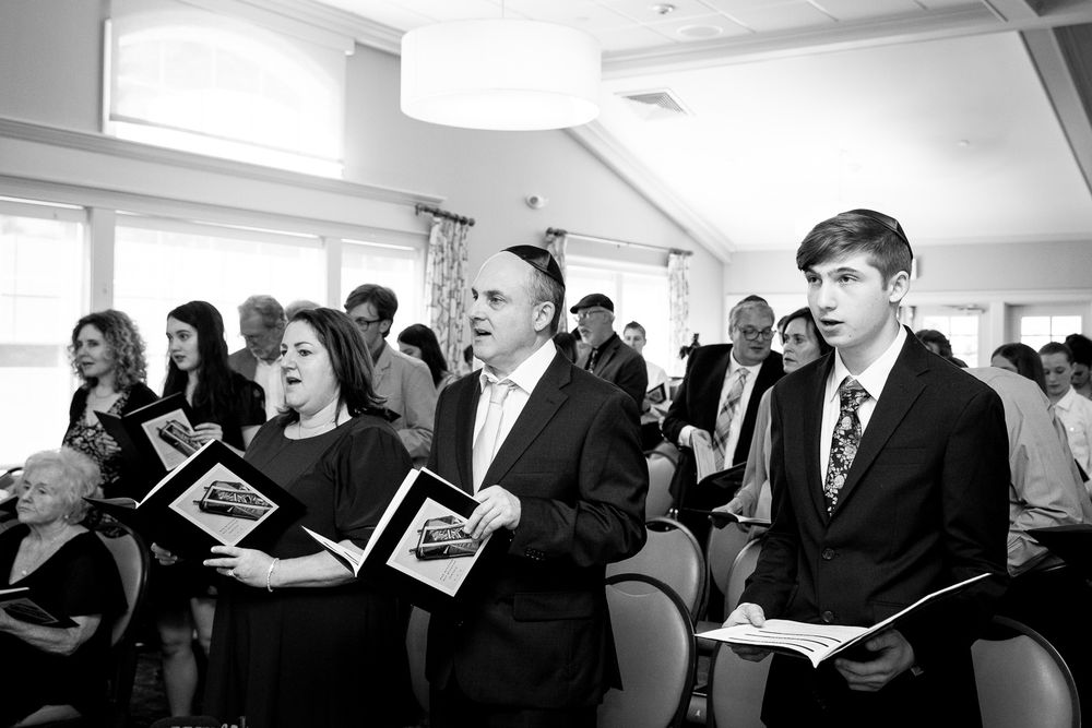 People stand in rows holding songbooks during a religious service.