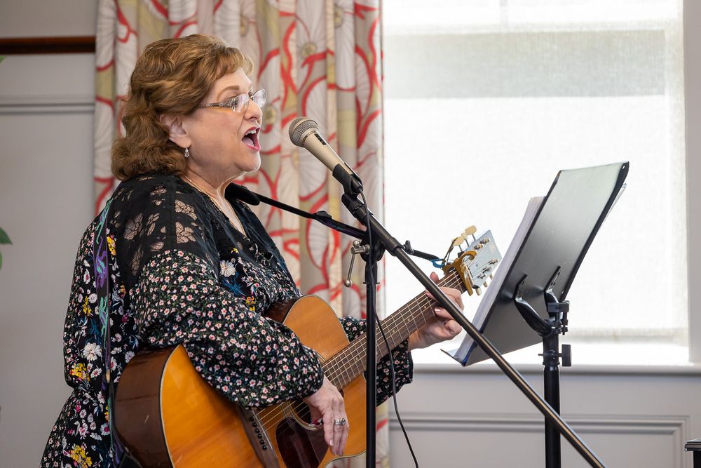 A musician performs with an acoustic guitar while singing into a microphone.