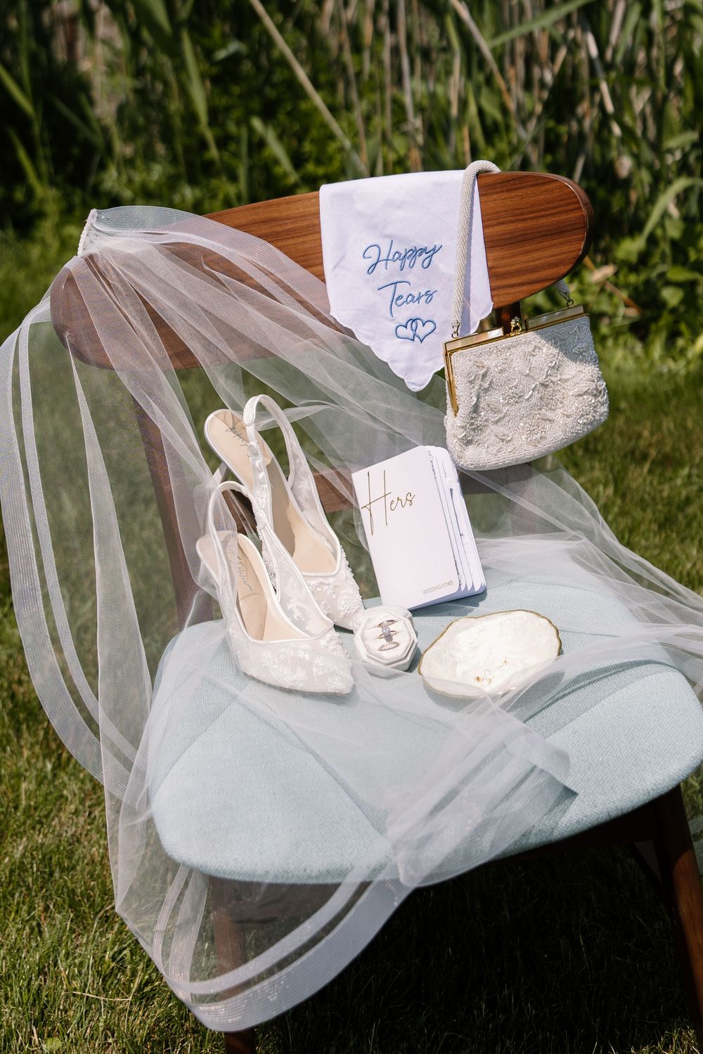 Wedding shoes displayed on light blue tulle fabric with name cards at an outdoor venue.