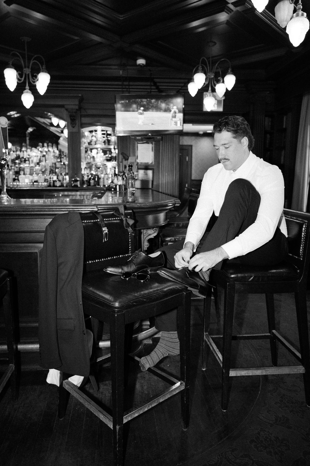 A person in formal attire plays a grand piano in a dimly lit bar or restaurant setting.