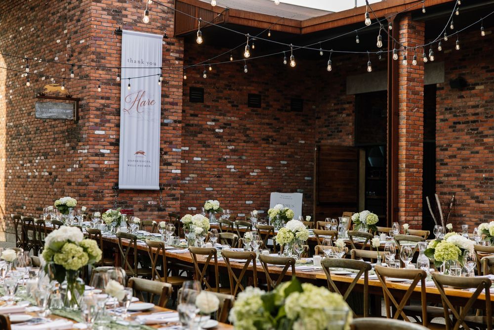 Elegant wedding reception tables decorated with white hydrangea centerpieces in a rustic brick-walled venue.