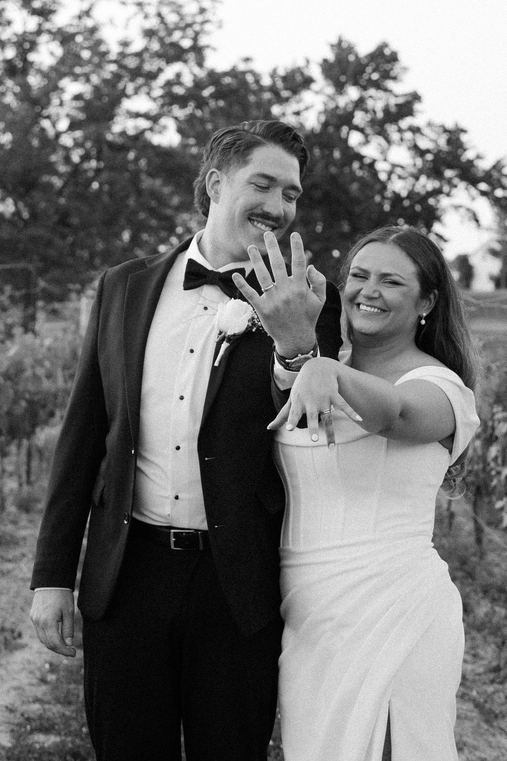 Newlyweds share a joyful candid moment together outdoors in formal wedding attire.