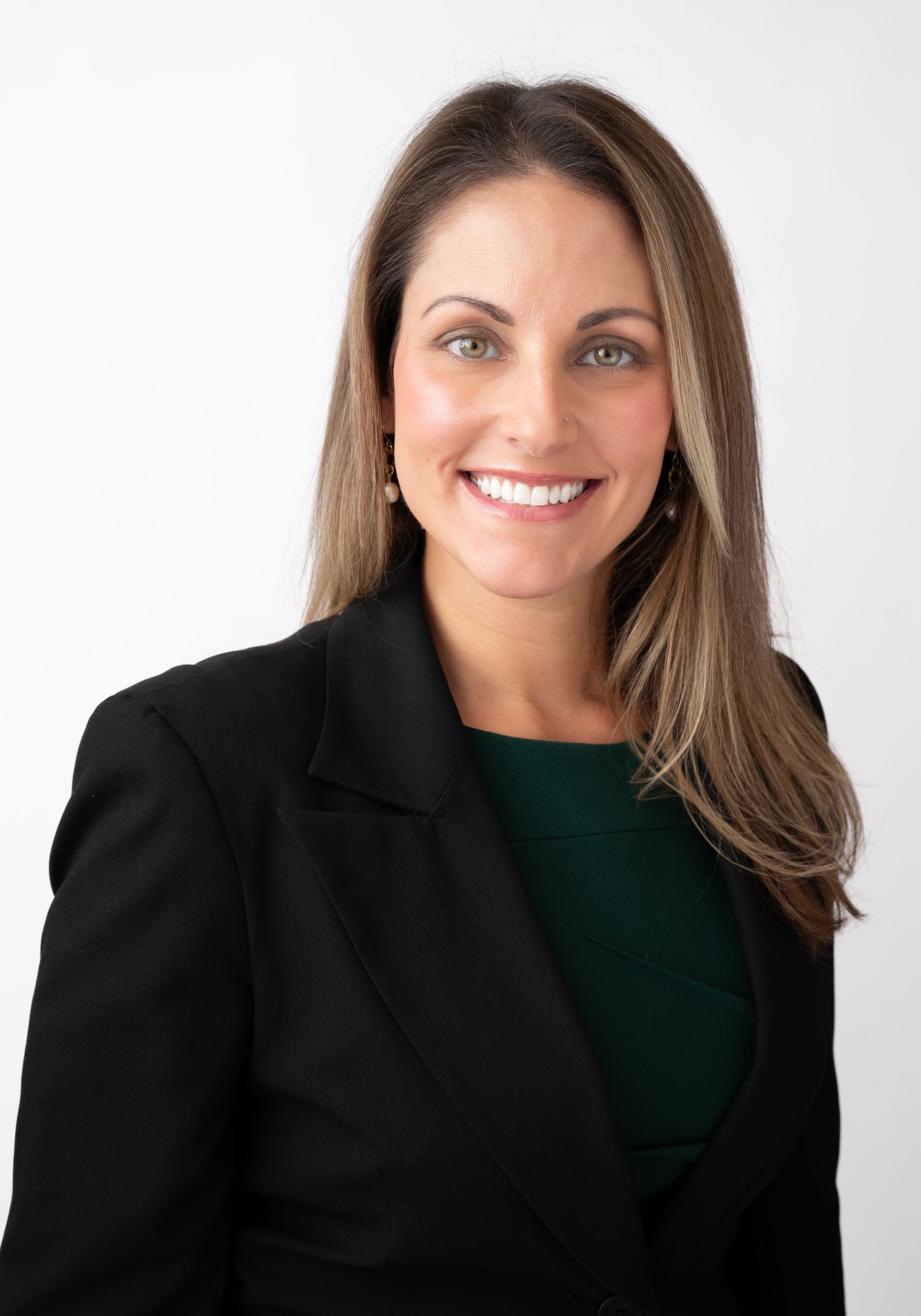 Professional portrait of person in black blazer and dark green top against white background.