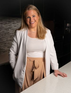 Business portraits in a white blazer and tan pants at a modern office setting.
