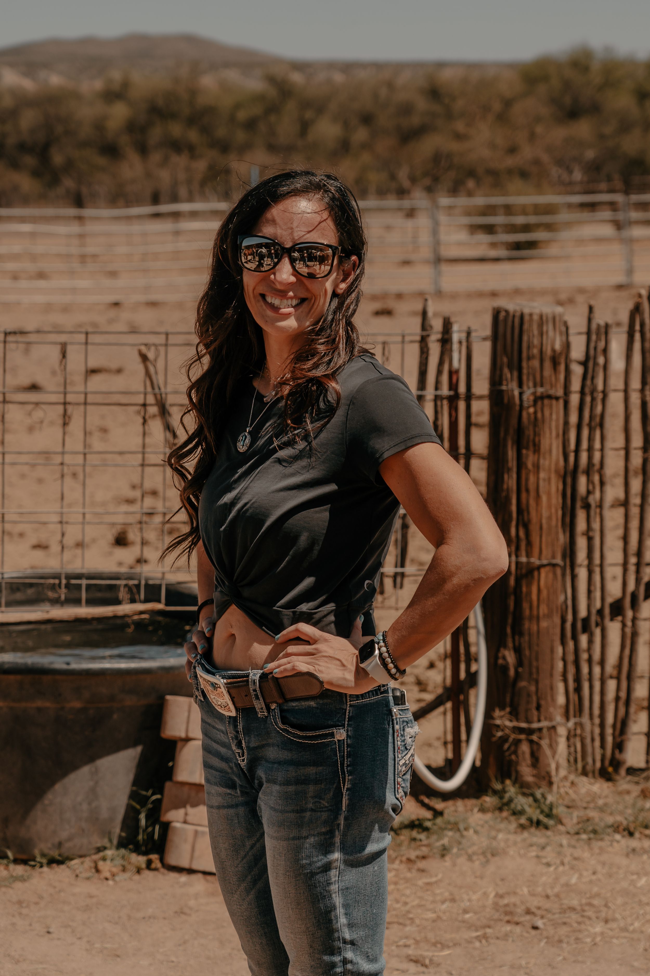 Western style portrait at a ranch with wooden fence and desert landscape in background.