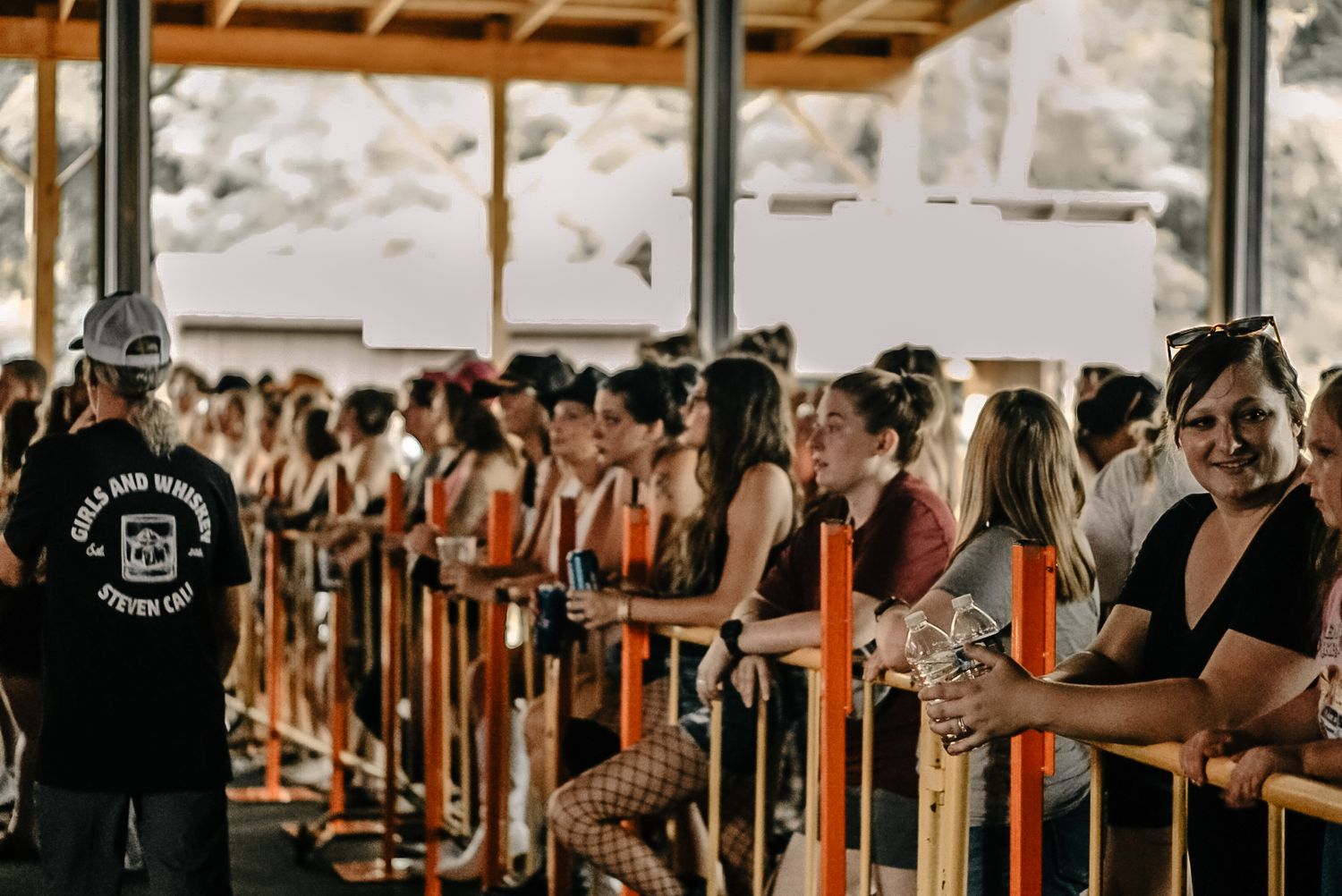 Crowd of people lined up along railings at an outdoor venue or event.