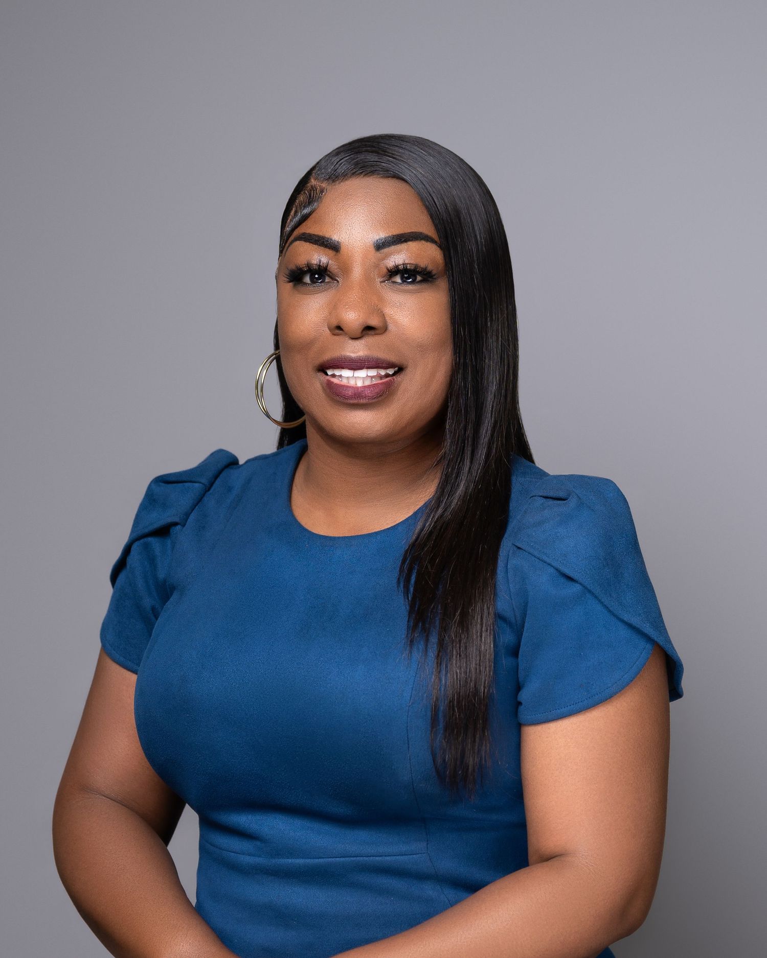 Professional portrait in blue dress against gray studio background.