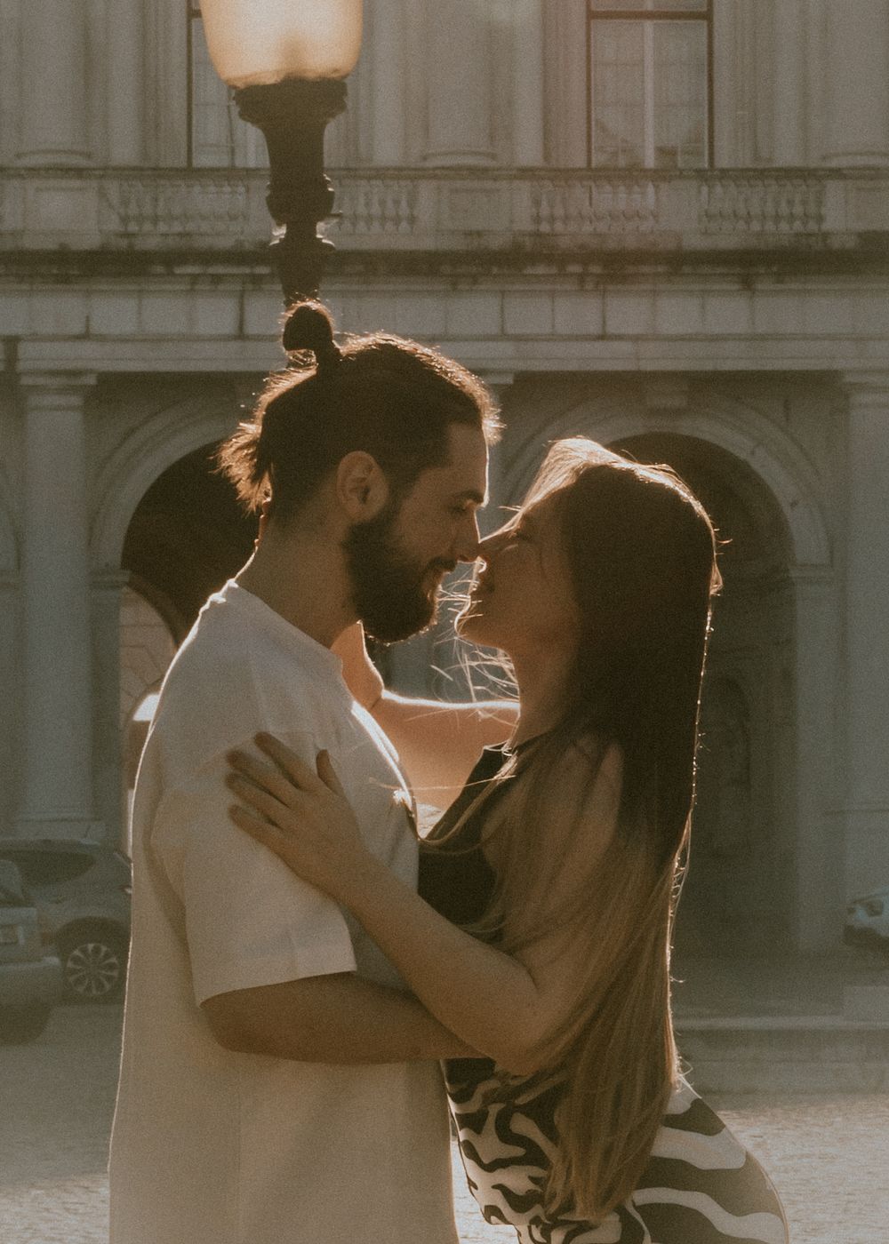 Romantic couple embracing in front of historic architecture during golden hour.