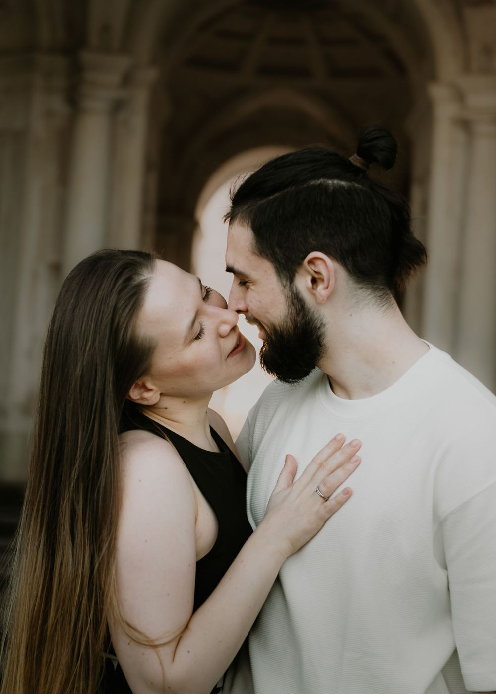 Intimate couple portrait under ornate archway in warm lighting.