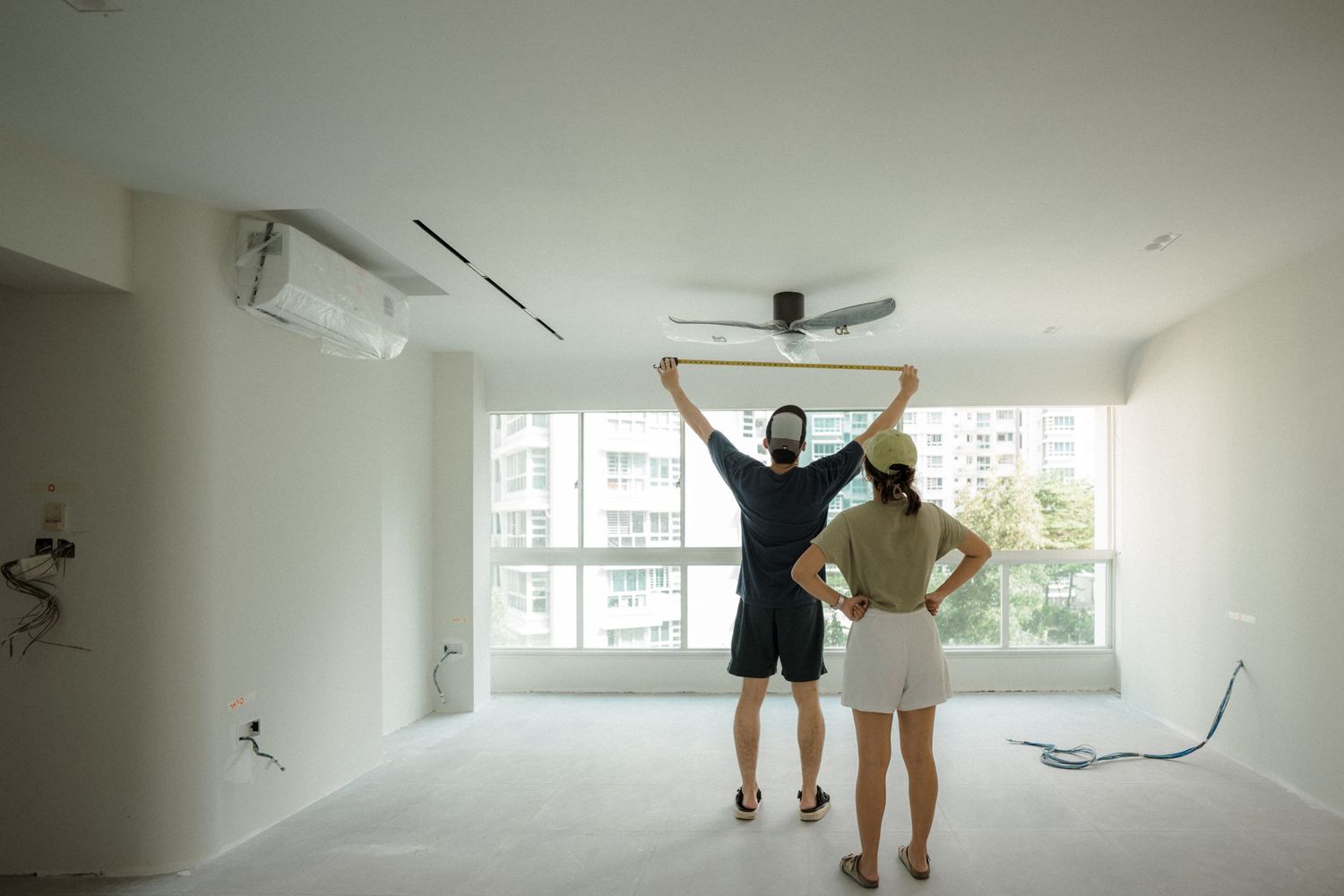 Two people looking out large windows in an empty white room with modern fixtures.