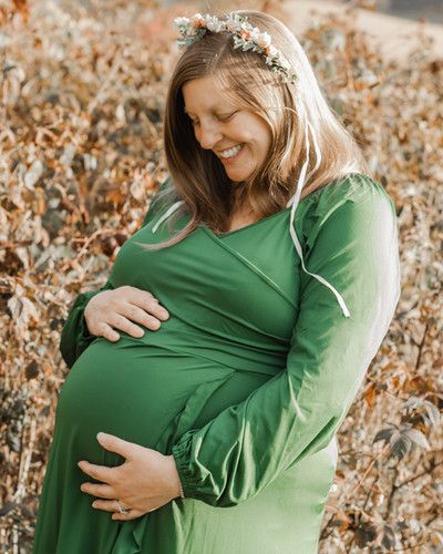 A visibly pregnant mother gazes at her cradled belly