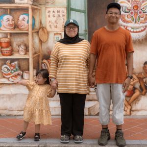 Family posed in front of a colorful mural wall with traditional Chinese artwork and decorations.