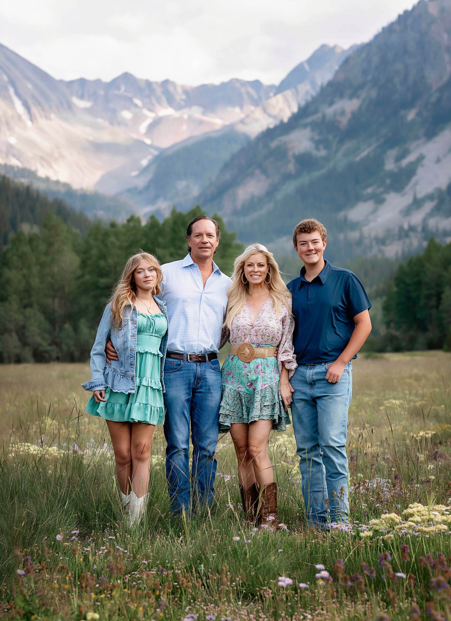 A beautiful family taking a photo together with the PineCreek mountains behind them