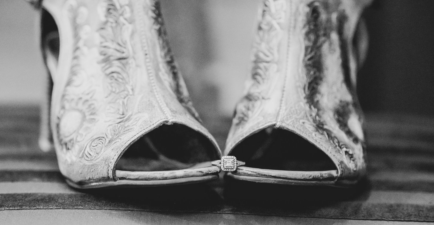 Close-up of vintage-style lace bridal shoes with peep-toe design on wooden floor.