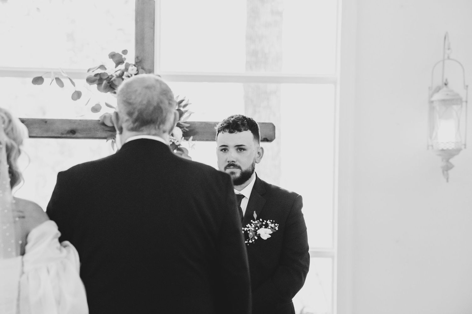 Black and white photo of a wedding ceremony moment in a brightly lit chapel.