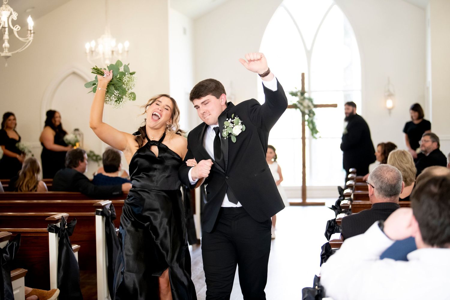 Wedding party members celebrating joyfully as they exit down the church aisle.