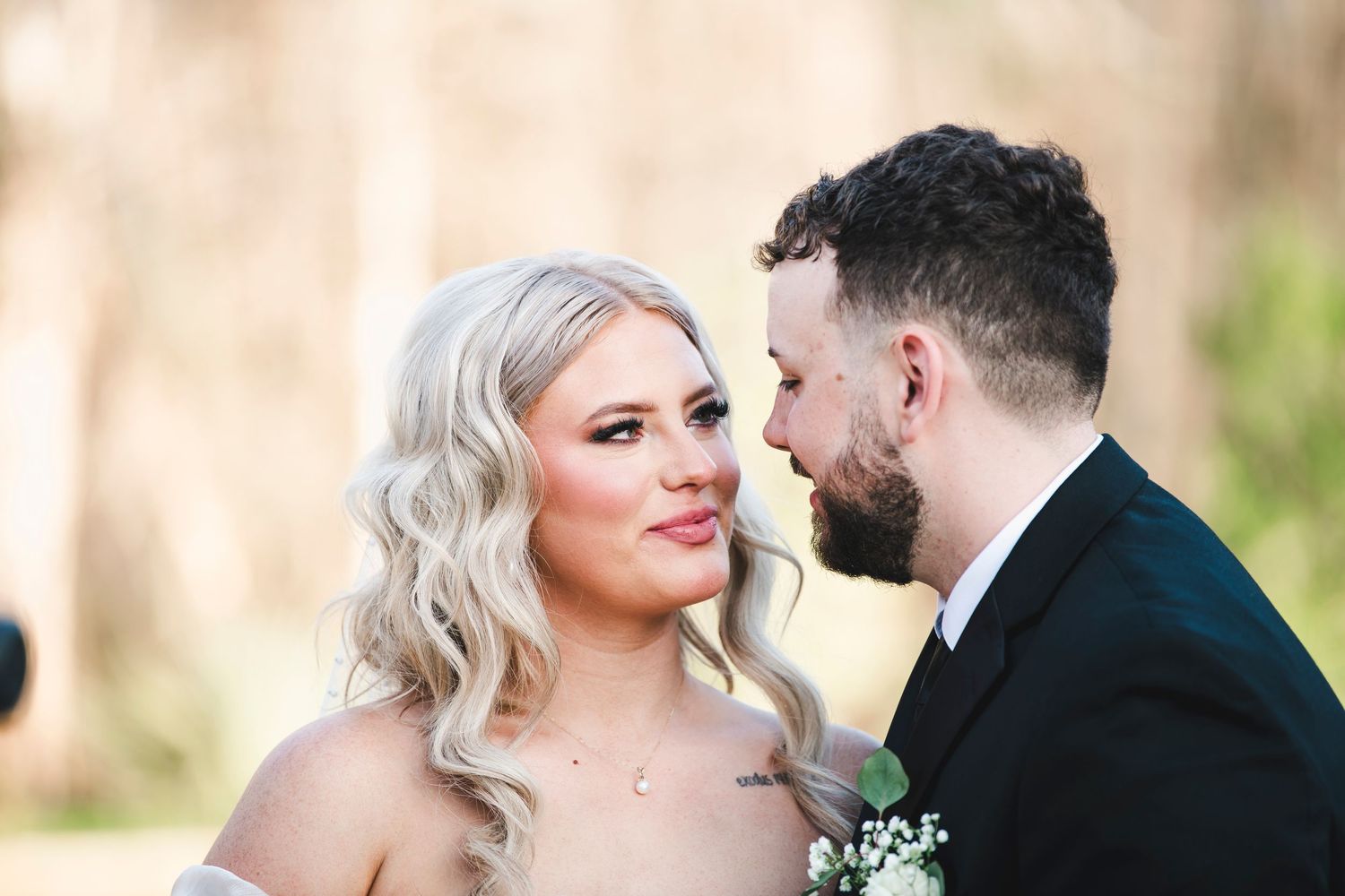 Intimate moment captured between newlyweds during outdoor portrait session.