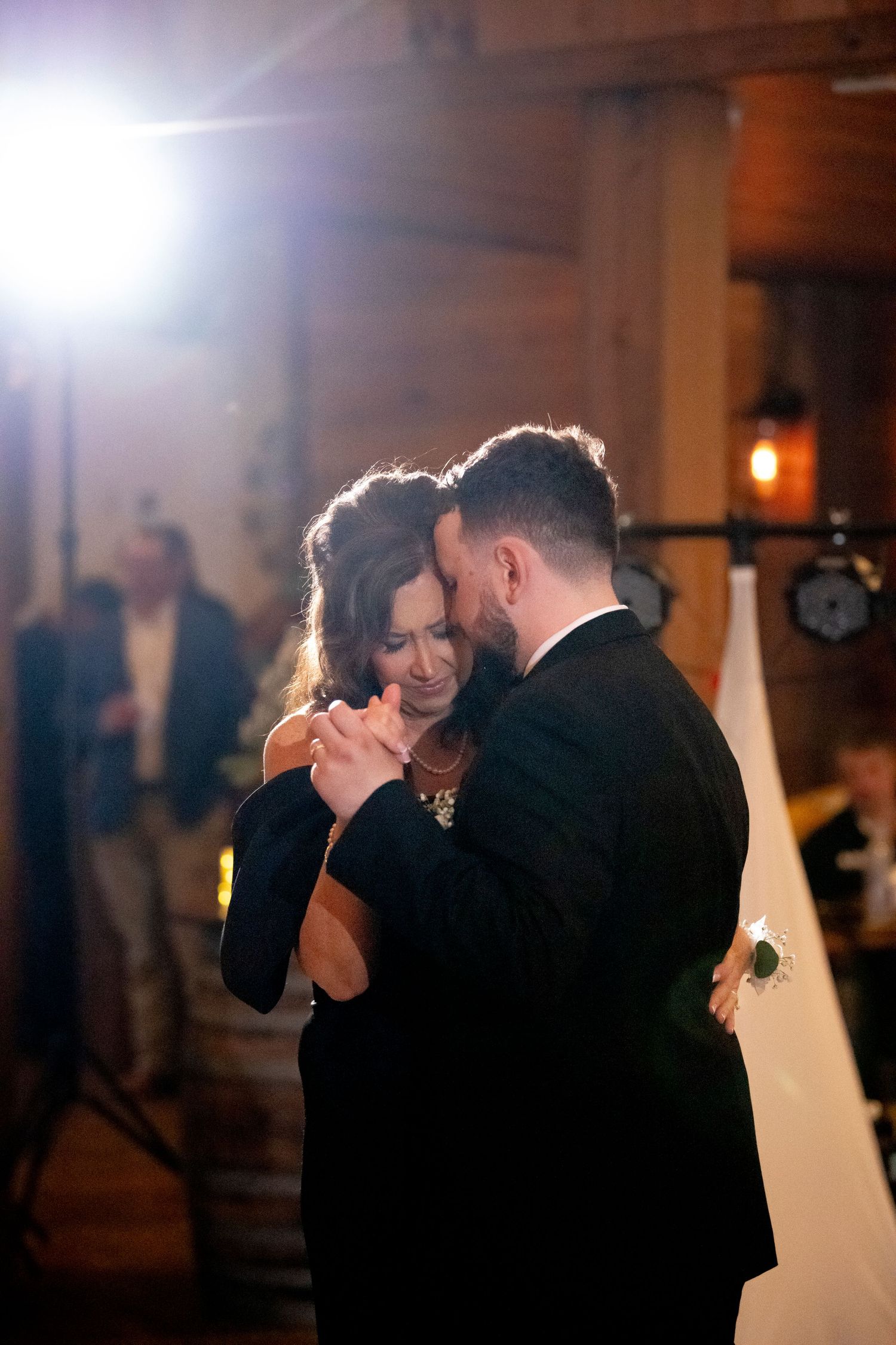 Couple shares an intimate dance moment under dramatic lighting at their wedding reception.