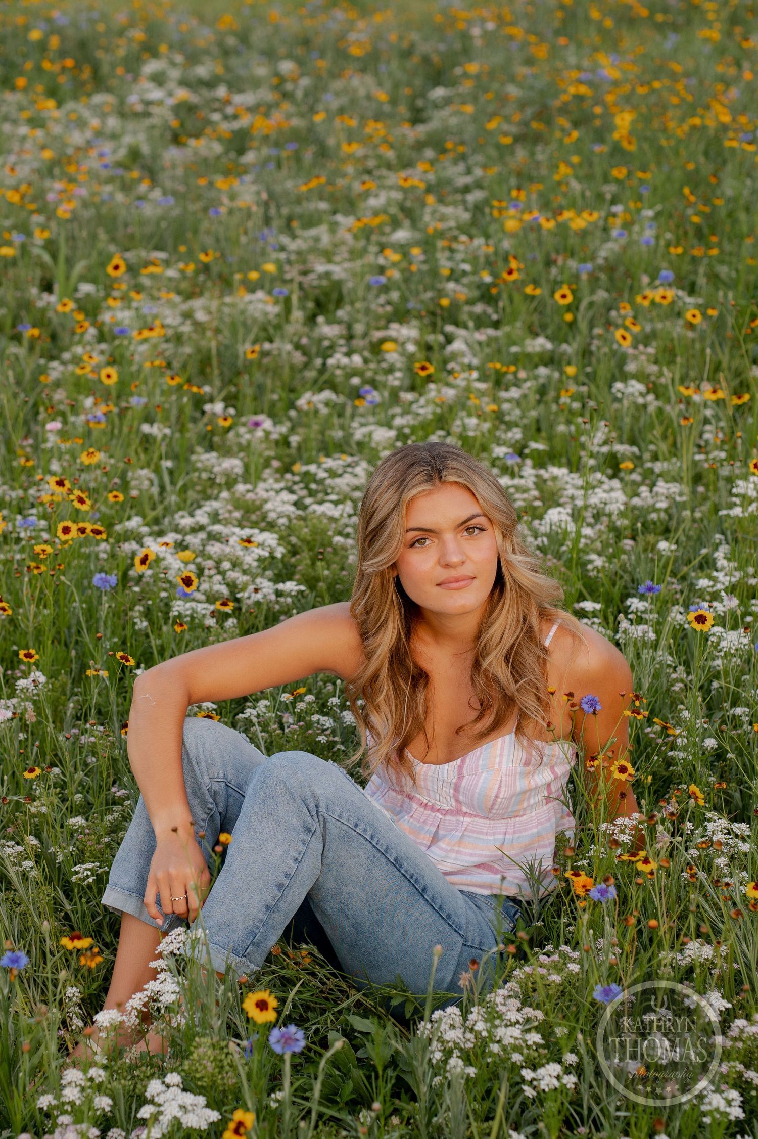 Relaxed summer portrait in a meadow filled with yellow and white wildflowers.