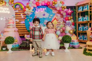 Festive birthday celebration setup with rainbow balloon arch and decorative wooden backdrop.