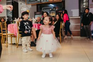 Celebratory party scene with tulle dresses and casual attire against indoor venue backdrop.