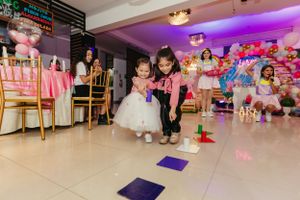 Party activities in progress on a decorated indoor venue floor with purple lighting.
