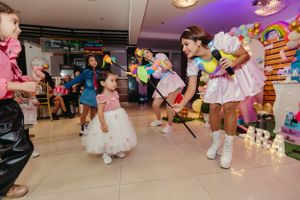 Active party games and dancing in progress at indoor celebration with balloon decorations.