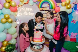 Birthday celebration moment with cake and balloon decorations in pastel colors.