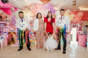 Festive celebration in a pink-decorated party room with colorful ribbons and decorations.