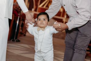 Small child in white outfit taking first steps in church aisle.