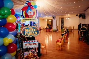 Circus-themed party venue with balloon arch and festive welcome sign.