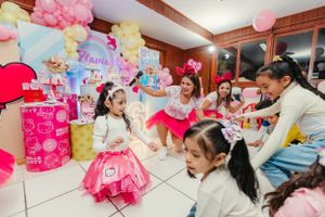 A pink-themed birthday celebration with children sitting and playing on the floor.