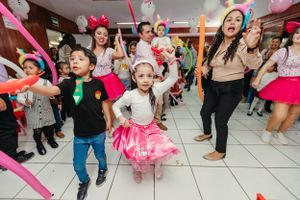 Children dancing and celebrating at a colorful indoor birthday party with balloons and decorations.