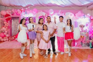 Group photo at a pink-themed Barbie celebration with balloon decorations.