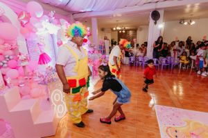 Entertainment performers interacting with guests at a pink-decorated party venue.