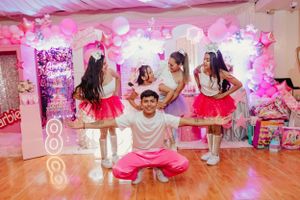Dance performance on a wooden floor with pink balloon decorations in the background.