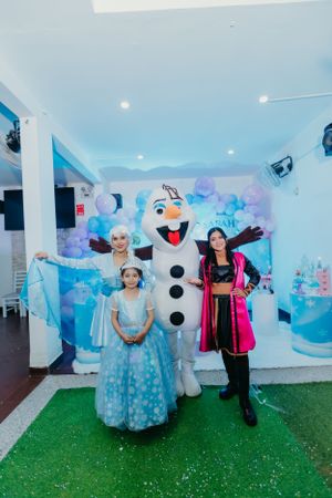 A Frozen-themed party setup featuring an Olaf character mascot against a winter backdrop.