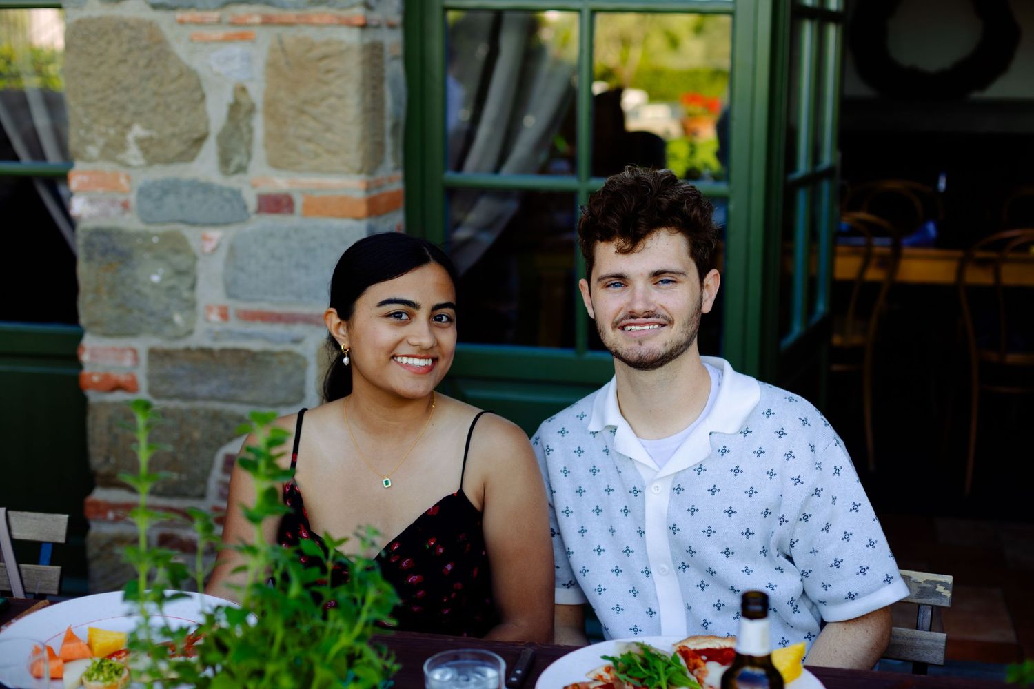 Couple dining outdoors at rustic restaurant with stone architecture.