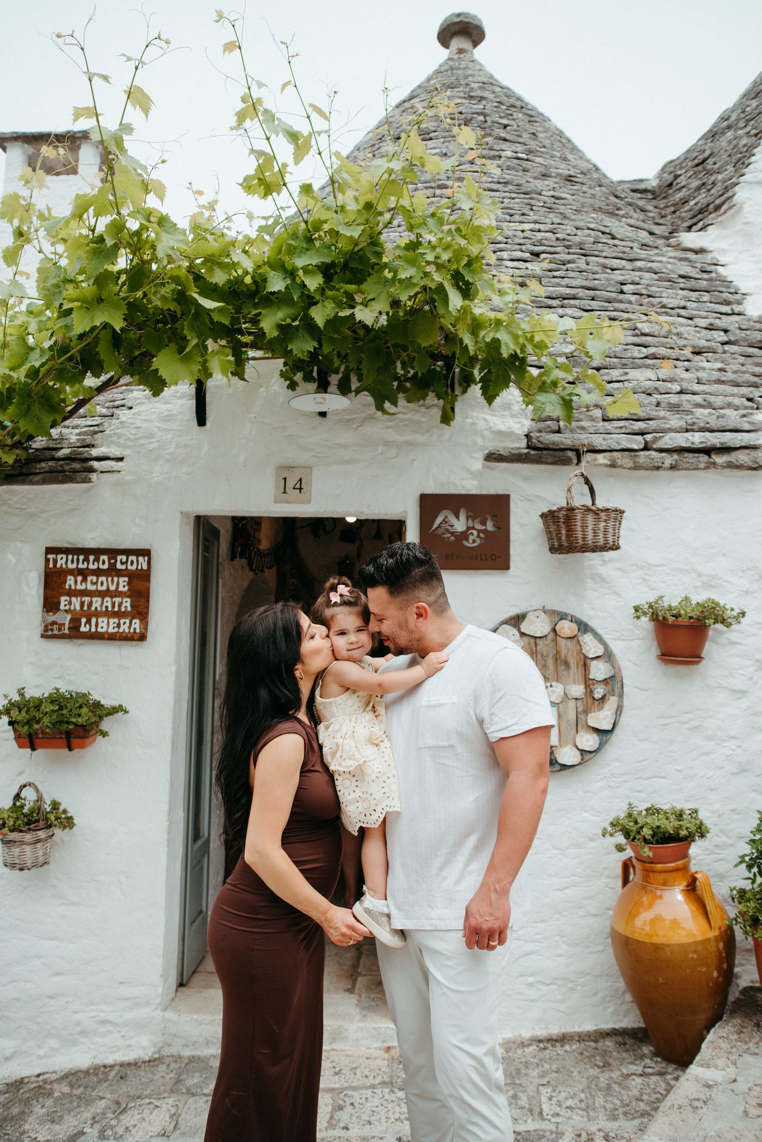Couple embracing outside traditional whitewashed trullo house with rustic decor.