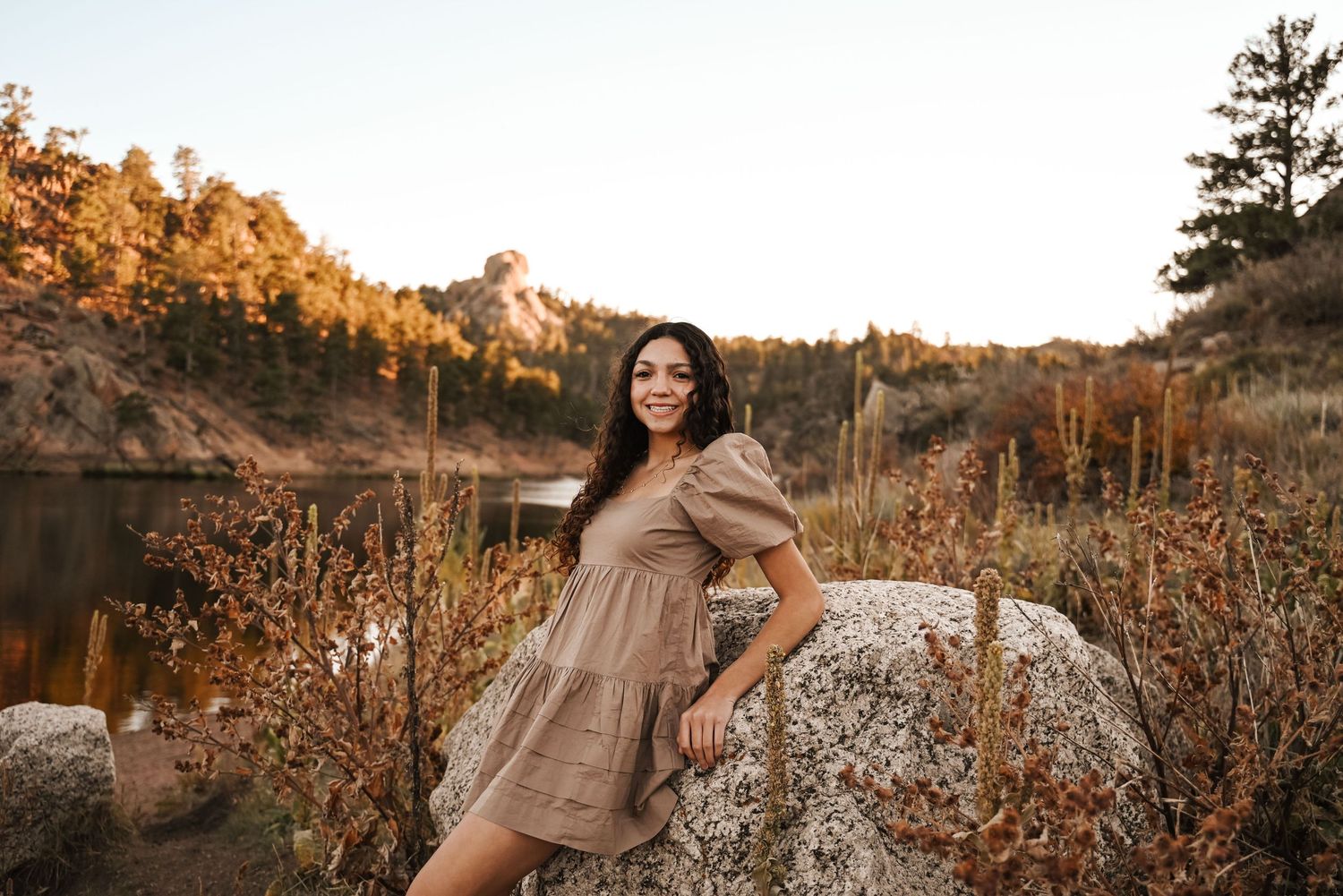 A scenic outdoor photoshoot at sunset with a rustic backdrop of mountains and natural terrain.