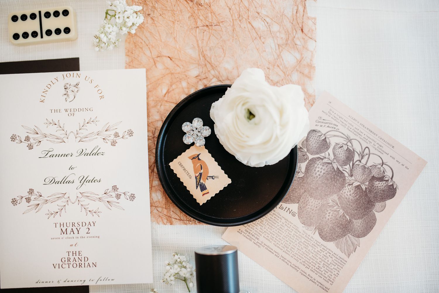 Wedding invitation and floral details on textured peach background with white flower.