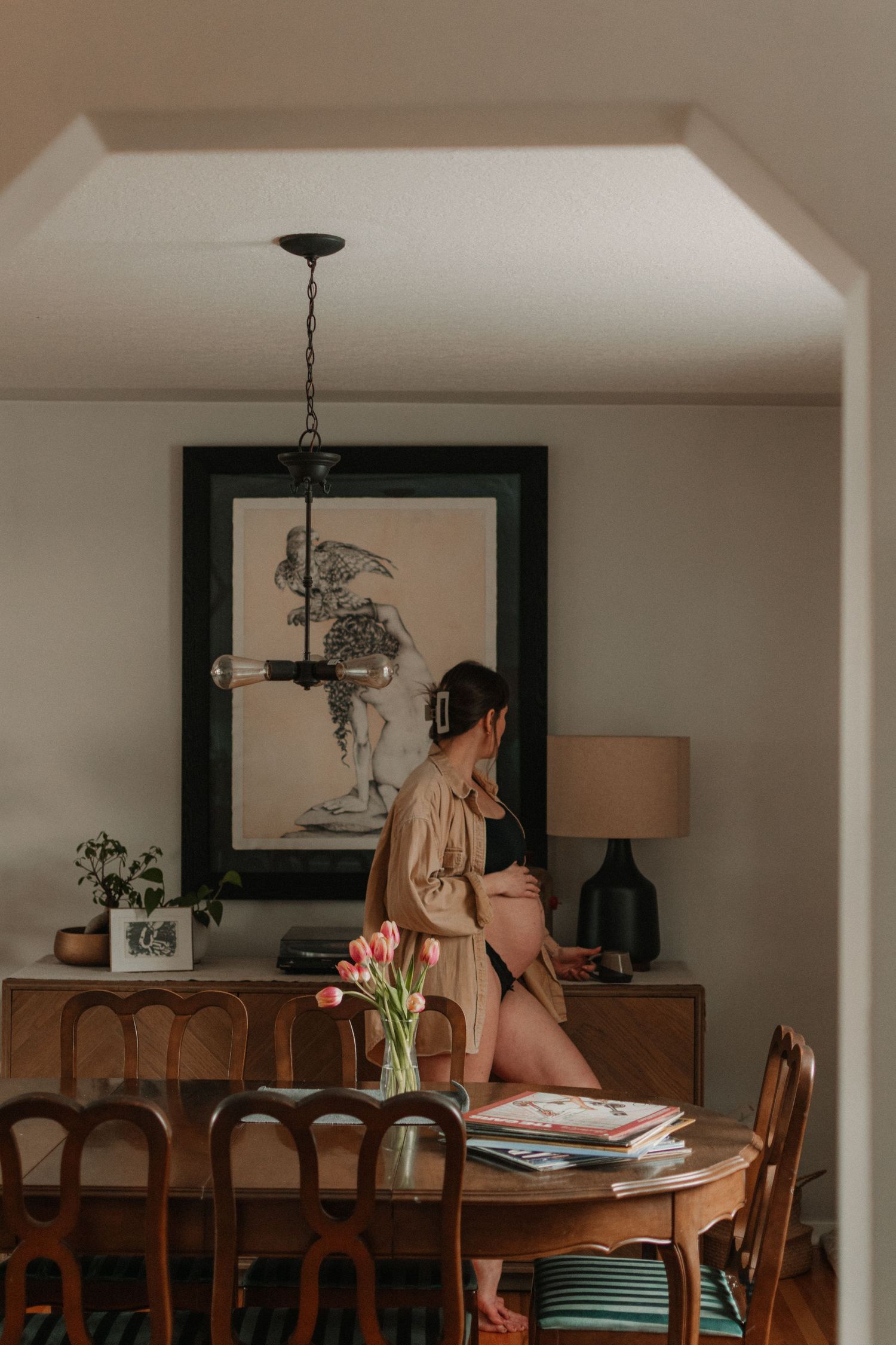 Interior scene with dining table, wooden furniture and decorative artwork in warm lighting.