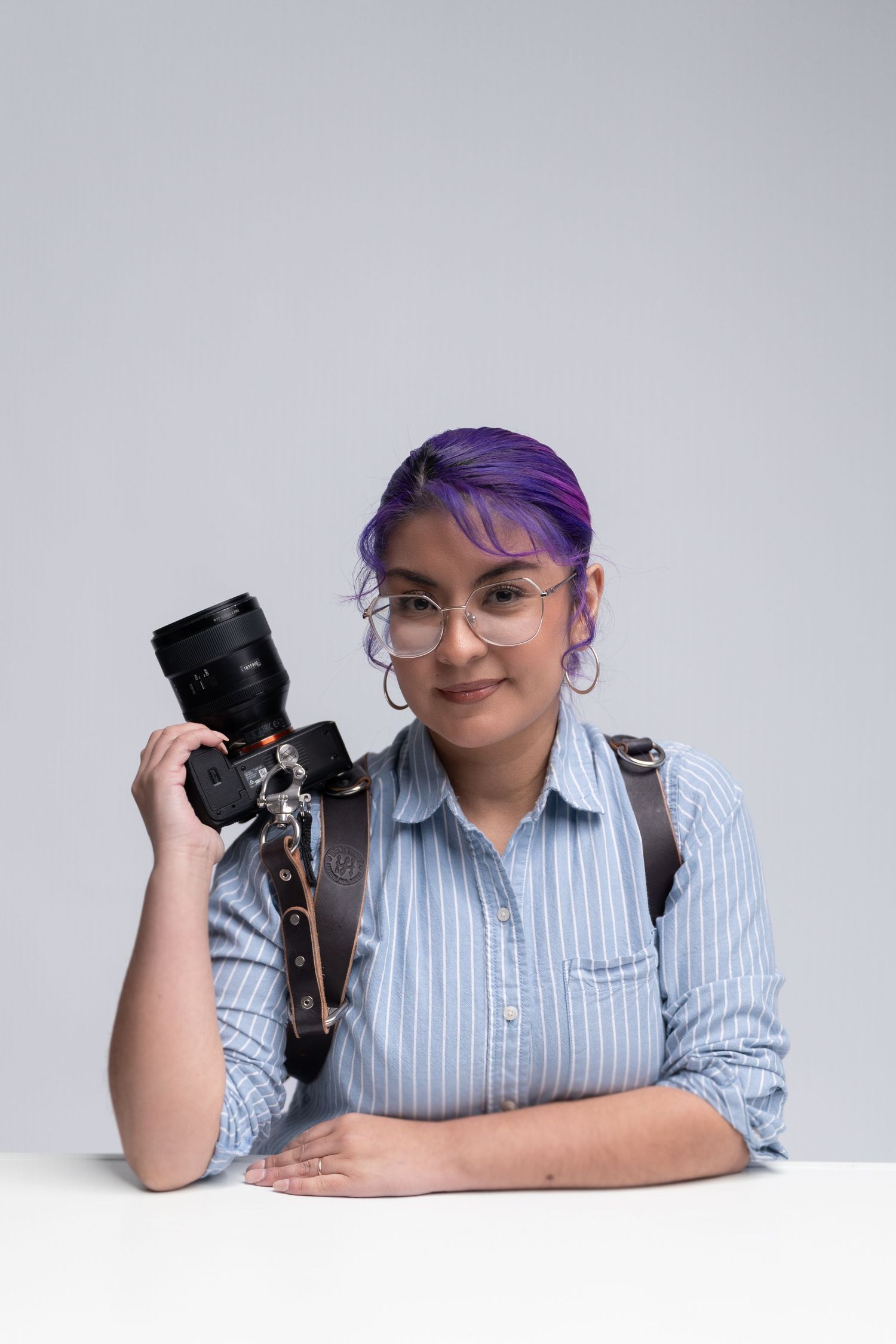 Professional photographer poses with camera equipment on white background.